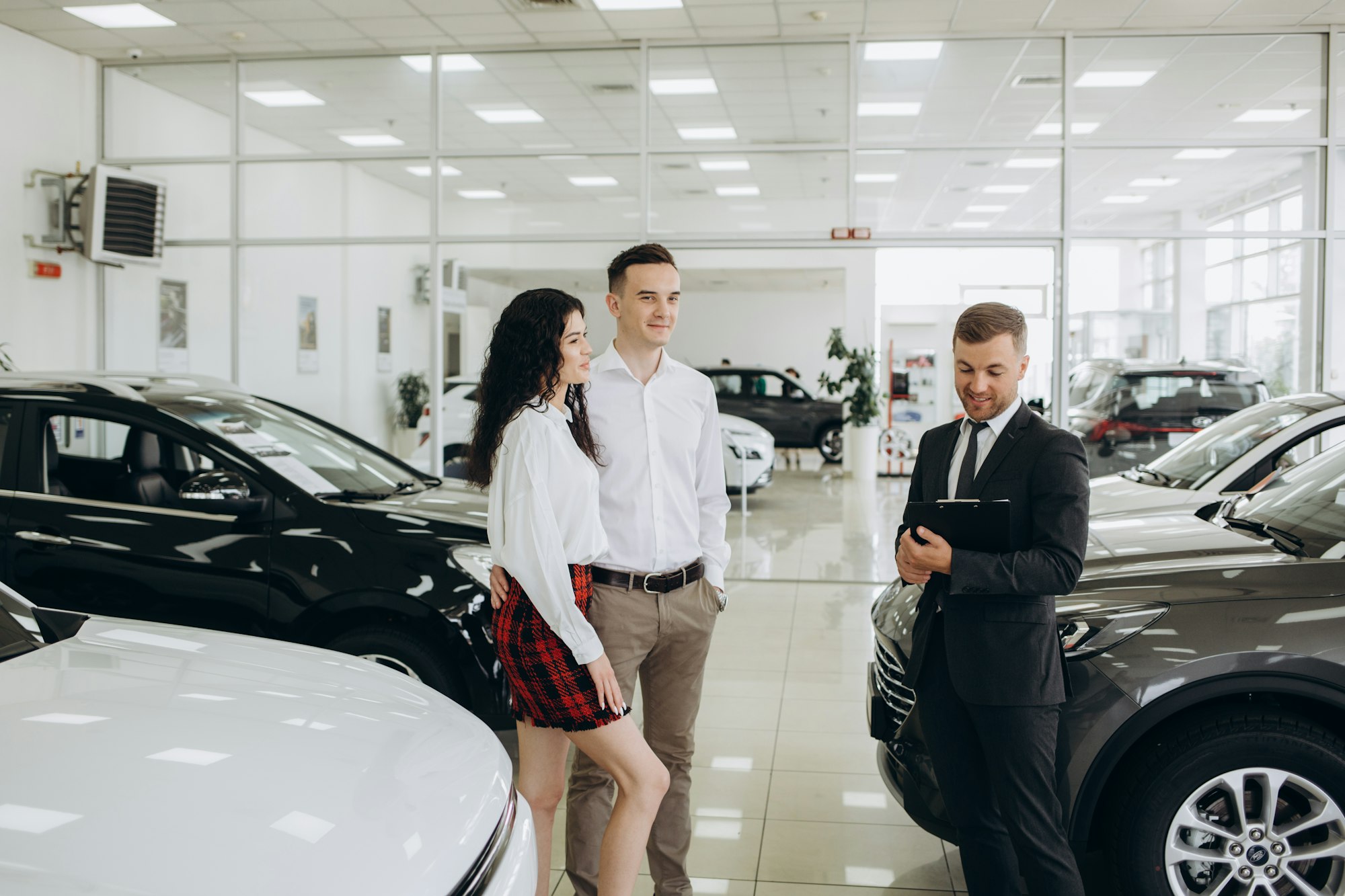 Car dealer showing car to couple in showroom